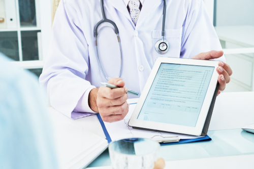 Image of a clinical trial specialist showing a patient some data on a digital tablet