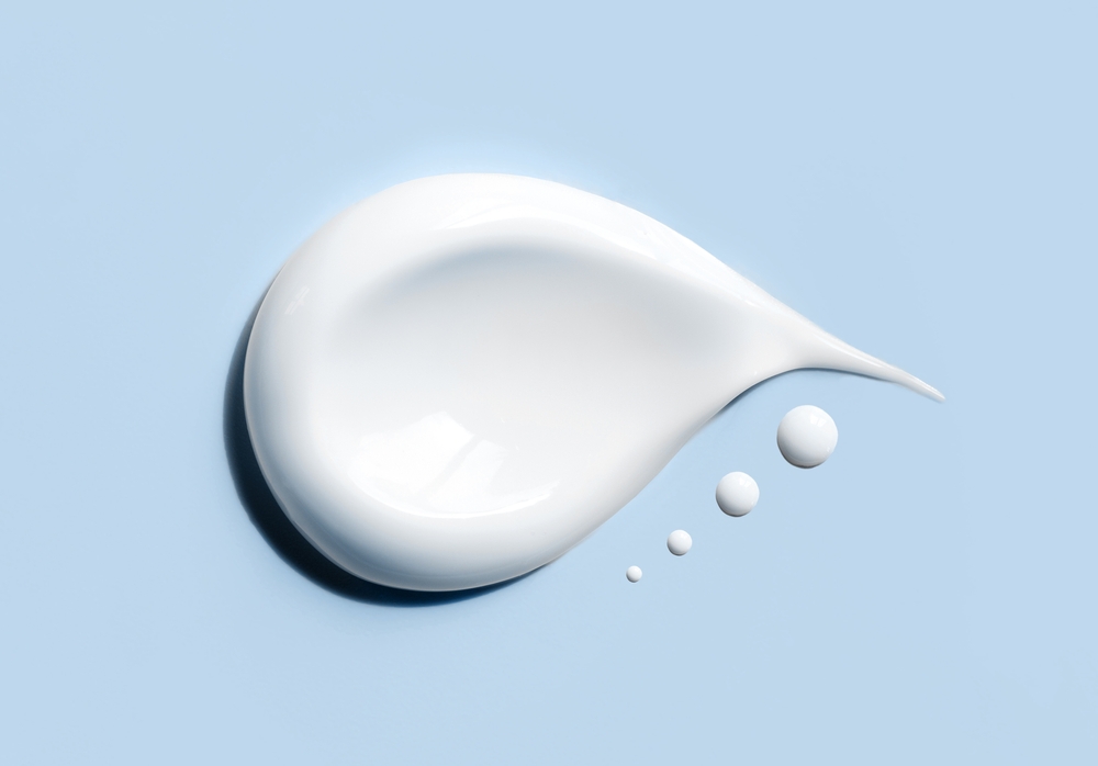 A droplet of moisturizing cream on a light blue surface.